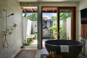 edles badezimmer mit grosser stein badewanne und privater aussen dusche im luxuriösen designer hotel und resort como parrot cay auf den turks- und caicoinseln in der karibik die terrasse ist durch wände abgetrennt